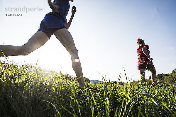 Zwei Läuferinnen laufen auf einem grasbewachsenen Feld
