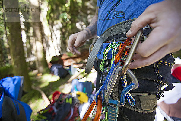 Ein Kletterer befestigt eine Karabinerschnellverbindung an seinem Klettergurt.