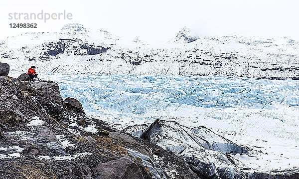 Einziger Beobachter mit Blick auf die Spalten eines Gletschers in der isländischen Landschaft