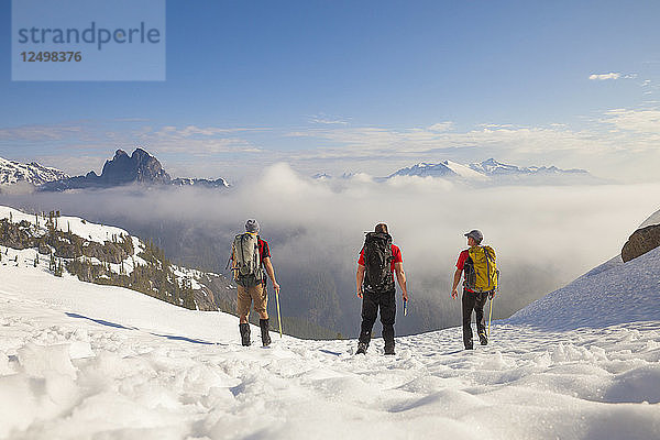 Drei Rucksacktouristen überqueren ein Schneefeld nach einem Ausflug in die Berge von British Columbia  Kanada.