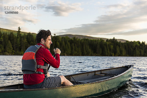 Ein Mann paddelt sein Kanu auf dem Long Pond in den nördlichen Wäldern von Maine nahe Greenville  Maine