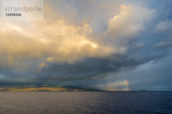 Ein Regenbogen unter einem stürmischen und bewölkten Himmel über der Insel Maui.