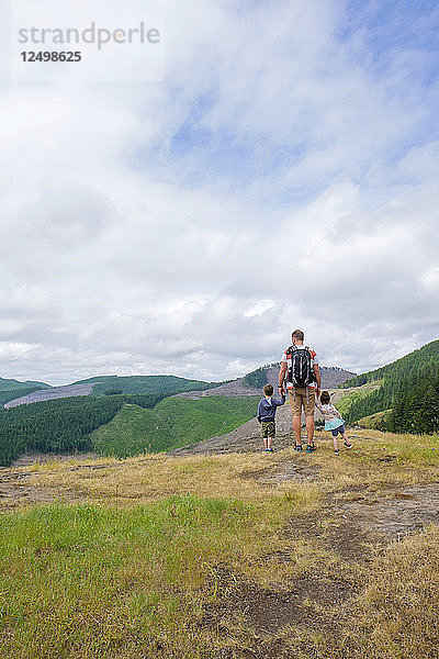 Vater mit seinen zwei kleinen Kindern beim Wandern auf einer Klippe in Oregon