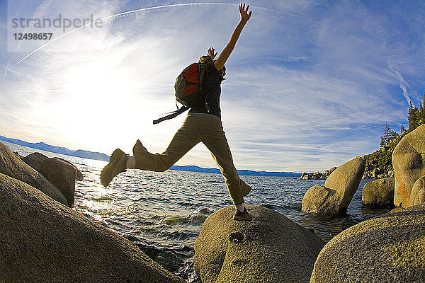 Frau springt auf Felsen im Lake Tahoe