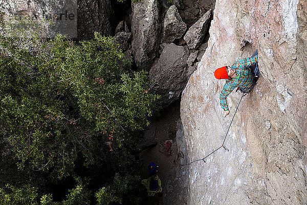 Ein männlicher Kletterer mit orangefarbener Mütze und mehrfarbigem Hemd klettert Family Jewel (5.10d) am Mount Gorgeous im Malibu Canyon State Park in Malibu  Kalifornien. Family Jewel ist eine sehr beliebte Sportkletterei im Malibu Canyon.