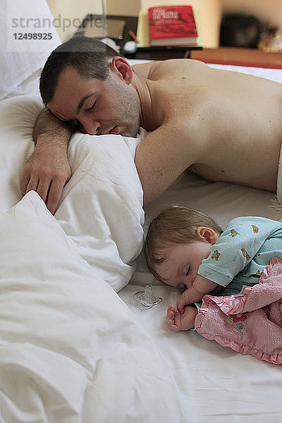 Tochter und Vater schlafen im Bett.
