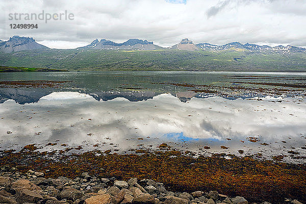 Berge spiegeln sich im Wasser eines Fjords in Nordisland