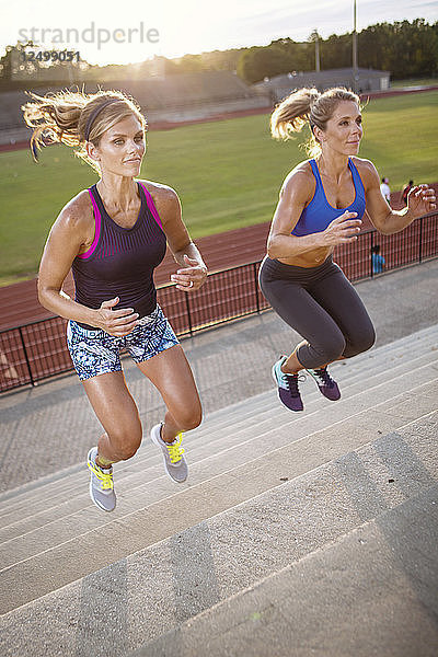 Zwei Frauen springen auf einer Treppe im Stadion