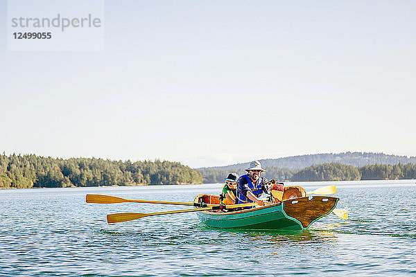 Ein Mann mit seinem Sohn und ihrem Hund in einem Ruderboot in Deer Harbor  Orcas Island  Washington  USA