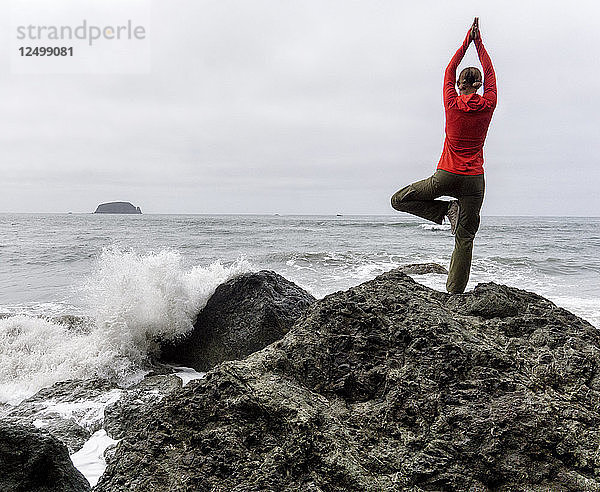 Eine Frau beim Yoga an der Küste des Olympic National Park