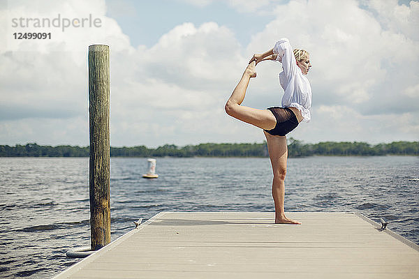 Eine junge Frau macht Yoga auf einem Steg mit Blick auf einen See in Panama City Beach  Florida.