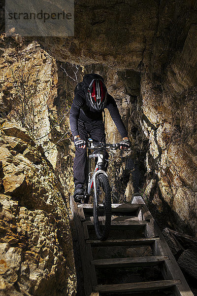Radfahrer Zeljko Rakic fährt mit seinem Fahrrad die in den Felsen eingelassene Holztreppe auf dem Berg Cemerno in Zentralserbien hinunter.