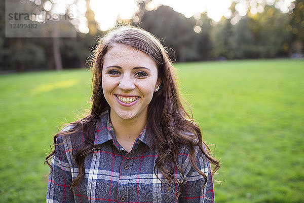 Ein weiblicher High-School-Schüler posiert für ein Porträt im Freien im Armitage Park in Eugene Oregon. Seniorenporträts sind eine beliebte Fotosession  mit der der Eintritt eines jungen Erwachsenen ins Erwachsenenalter gefeiert wird.