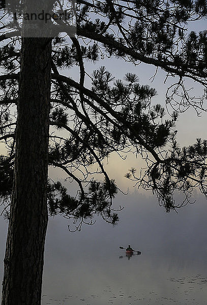 Ein Kajakfahrer genießt den Sonnenaufgang  während an einem kühlen Herbstmorgen Dampf aus dem Lake Pleasant in Conover  Wisconsin  aufsteigt.