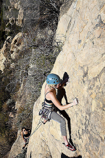 Eine Frau mit Tanktop und gestreifter Hose klettert The Rapture (5.8) am Lower Gibraltar Rock in Santa Barbara  Kalifornien. The Rapture ist eine sehr schöne und unglaublich gut abgesicherte Route auf der linken Seite des Lower Gibraltar Rock.
