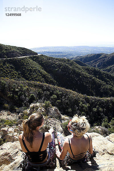 Zwei Bergsteigerinnen unterhalten sich über ihren Klettertag  während sie auf dem Lower Gibraltar Rock in Santa Barbara  Kalifornien  sitzen. Der Lower Gibraltar Rock bietet eine großartige Aussicht auf Santa Barbara und den Pazifischen Ozean.