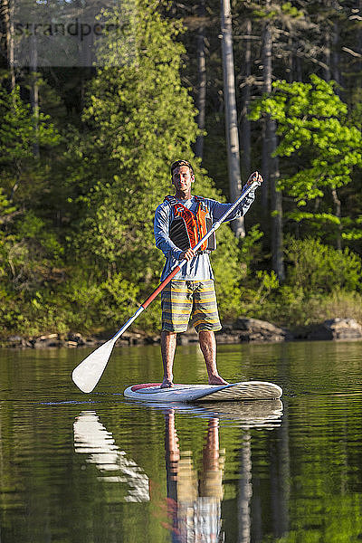 Ein Mann paddelt auf einem langen Teich in der Nähe von Greenville  Maine