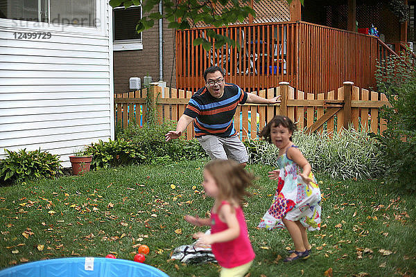 Ein Mann  der mit seinen Kindern im Hinterhof spielt