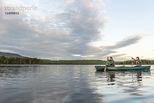 Ein junges Paar paddelt ein Kanu auf Long Pond in Maine's North Woods in der Nähe von Greenville  Maine