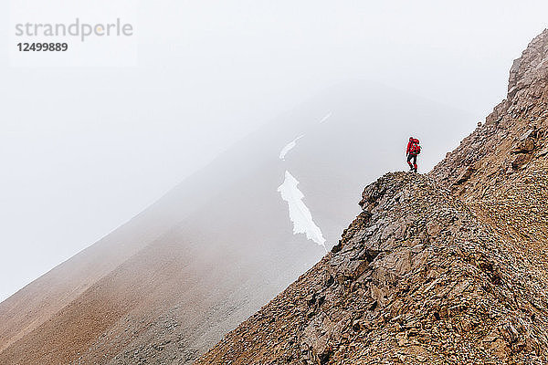 Eine Frau wandert auf einem Bergrücken im Nebel in den Delta Mountains  Alaska Range  Alaska  Usa