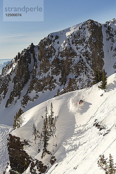 Extremskifahrer  der in extremem Gebirgsgelände den Hang hinunterfährt