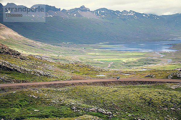 Distant View Of A Woman Rides Along A Mountain Road In North Iceland