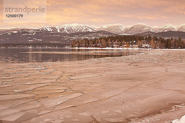 Whitefish Lake bei Sonnenuntergang mit gebrochenem Eis und weichem Licht auf Whitefish Mountain Resort