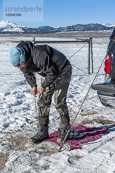 Mann schnürt Wathosenstiefel am Upper Owens River