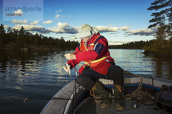Fischer hält einen Fisch in seinen Händen am Nipissing See