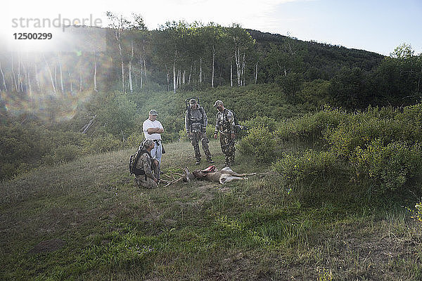 Eine Gruppe von Bogenjägern trifft sich auf einer Lichtung  um frisch erlegte Hirsche zu begutachten.