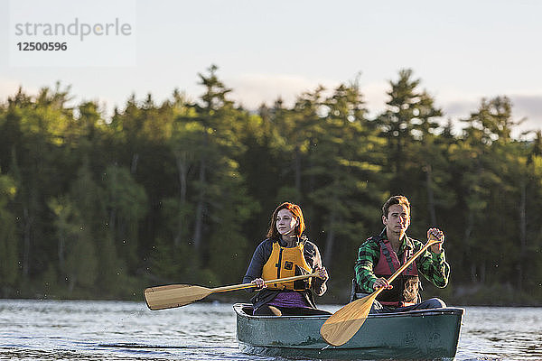 Ein junges Paar paddelt ein Kanu auf Long Pond in Maine's North Woods in der Nähe von Greenville  Maine