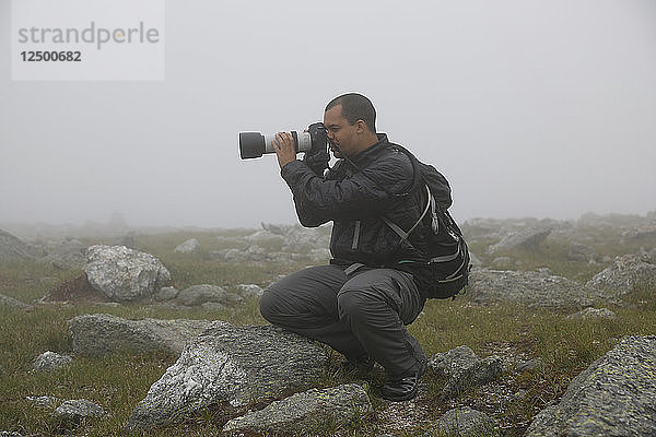 Männlicher Fotograf  der den Mount Washington bei starker Bewölkung fotografiert