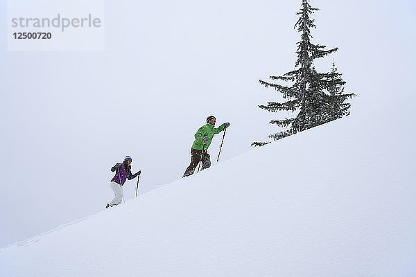 Ein Mann und eine Frau gehen mit Schneeschuhen einen Hang am Schweitzer Mountain in Sandpoint  Idaho  hinauf.