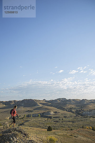 Eine erwachsene Frau genießt bei einer Tageswanderung die Aussicht im Theodore Roosevelt National Park in North Dakota.