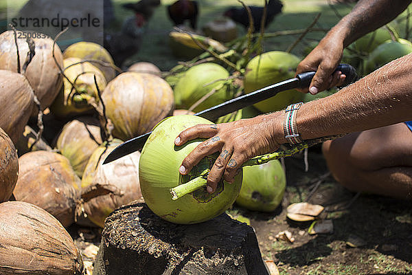 Blick auf einen Mann  der eine Kokosnuss öffnet.West Sumbawa.Indonesien.