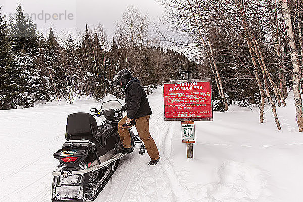 Mann steigt in der Nähe der kanadischen Grenze auf ein Schneemobil