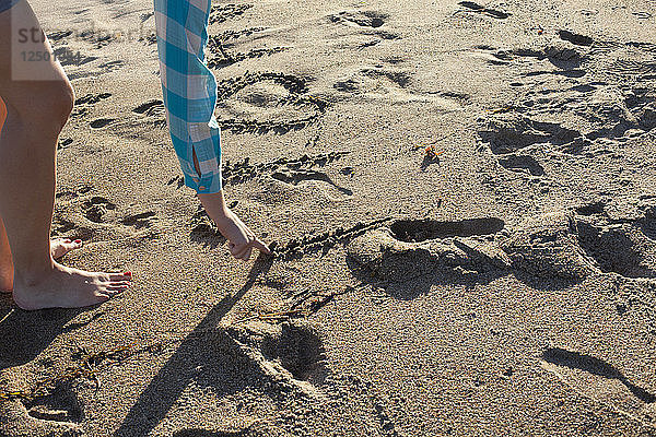 Frau schreibt romantische Botschaft mit Initialen in den Sand im Reid State Park