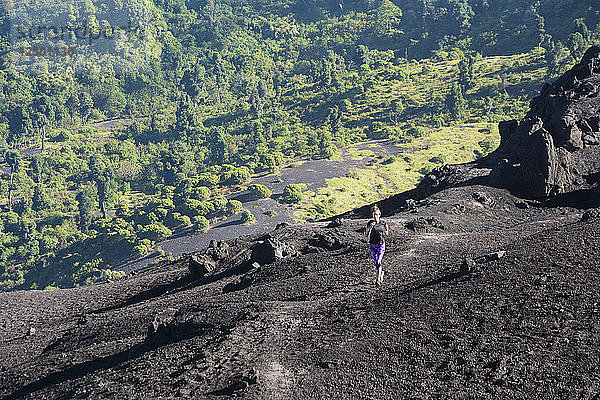 Eine junge sportliche Läuferin läuft auf dem schwarzen Sand des Pacaya-Vulkans  Guatemala