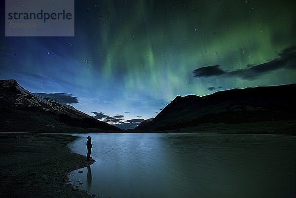 Person  die Aurora Borealis am Ufer des Sunwapta Lake im Jasper National Park beobachtet