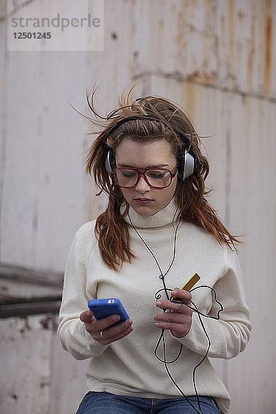Ein Mädchen im Teenageralter  das auf einem Parkplatz zu den Klängen ihres Smartphones abrockt. Boise  Idaho.