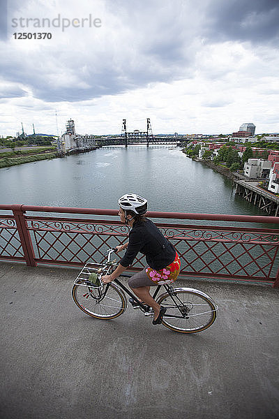 Eine Frau fährt über die Broadway Bridge in Portland  Oregon. Ein Blick auf die Stadt ist gleich dahinter.