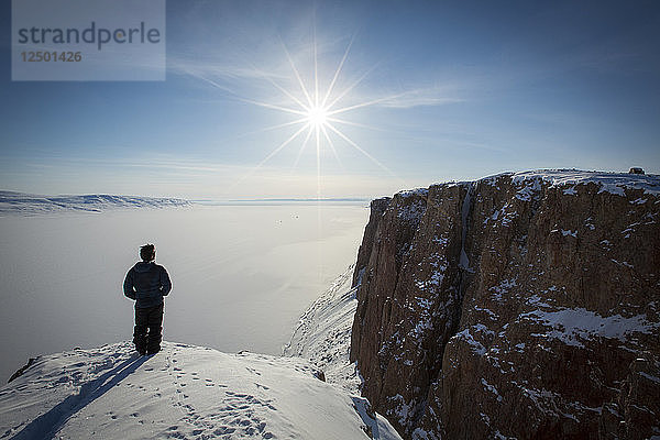 Person stehend auf schneebedeckter Klippe in der Arktischen Bucht
