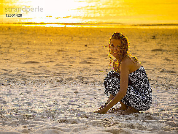 Junge Frau am Strand bei Sonnenuntergang.