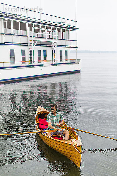 Mann fährt auf einem kleinen antiken hölzernen Ruderboot auf dem Sankt-Lorenz-Strom in New York