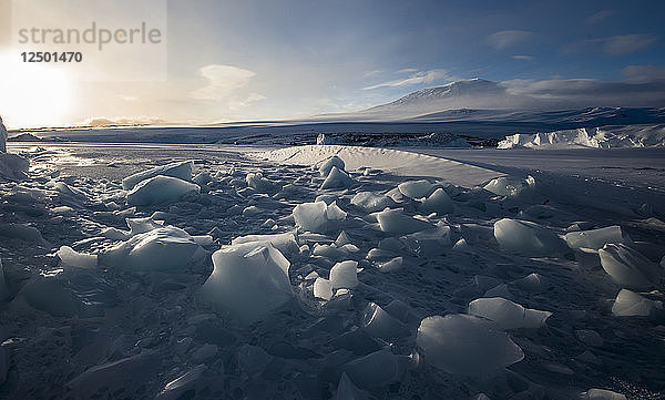 Die zerbrochene Oberfläche des gefrorenen McMurdo Sound in der Ross Sea Region der Antarktis mit dem Mount Erebus im Hintergrund.