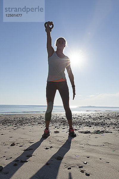 Frau stehend mit Kettlebell tun Übung am Strand