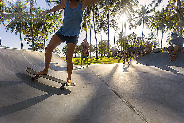 Menschen Skateboarding in Skate-Rampe unter Palmen