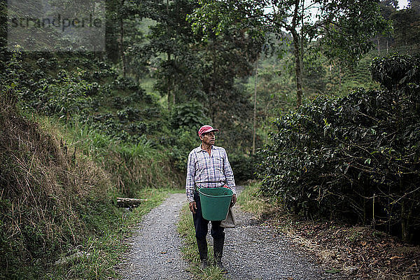 Das Porträt eines älteren Mannes auf einer Straße in einem Bauernhof nach der Ernte frischer Kaffeebohnen im ländlichen Hochland der kolumbianischen Kaffeeachse.