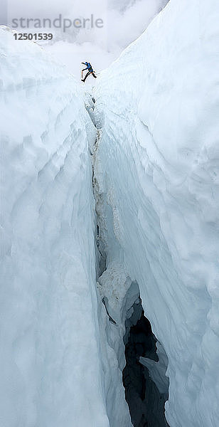 Low Angle View of Climber Steps Over A Large Crevasse On The Coleman Glacier