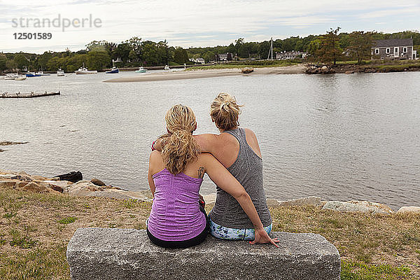 Zwei Frauen  die sich umarmen und auf das Wasser schauen.